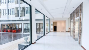 A spacious, modern hotel lobby with large glass windows, a polished floor, and a view of the outdoor seating area. - Orchid Riverview Hotel (Surat Thani)