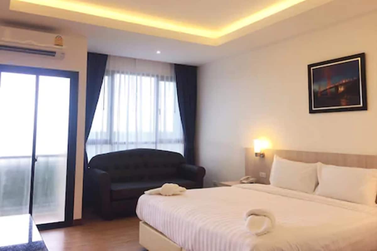 A hotel room with a bed, a chair, a desk, and a window with curtains.