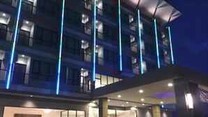 A modern hotel with a glass facade, multiple balconies, and a well-lit entrance. - Orchid Riverview Hotel (Surat Thani)