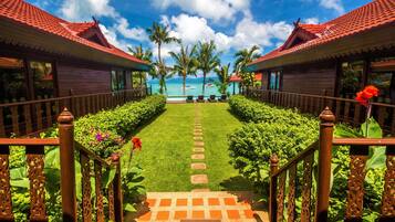 Stroll along the resort's scenic pathway, lined with lush greenery and palm trees, leading to the beautiful beach.