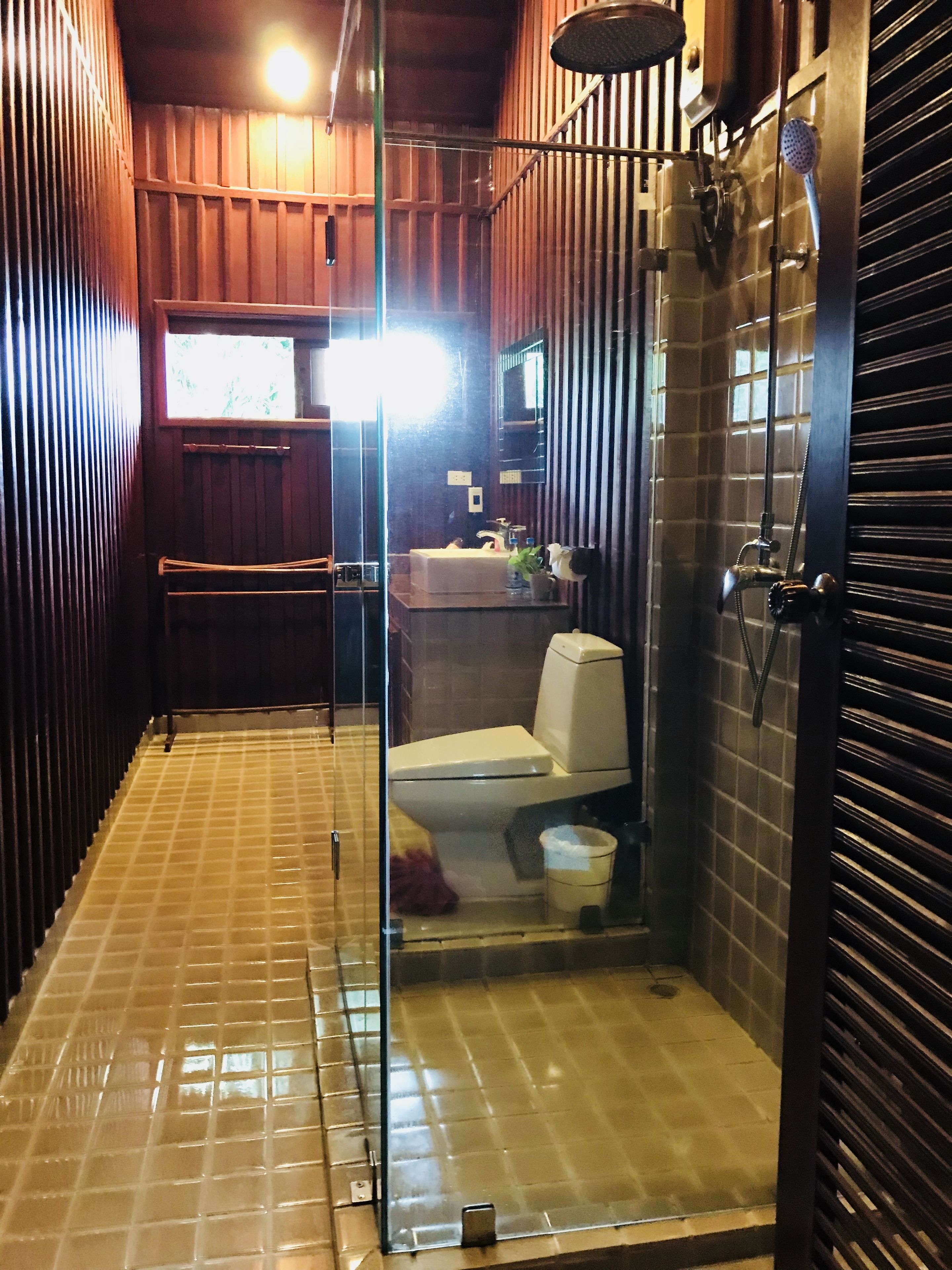 A bathroom with a glass partition, a toilet, a sink, and a shower area.