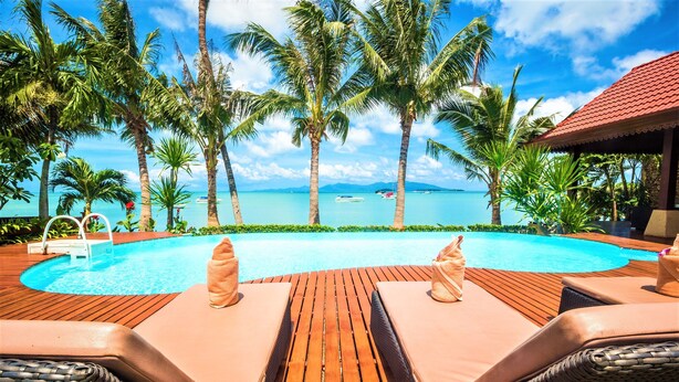 A poolside area with lounge chairs and a view of the ocean. - Erawan Villa Hotel (Koh Samui)