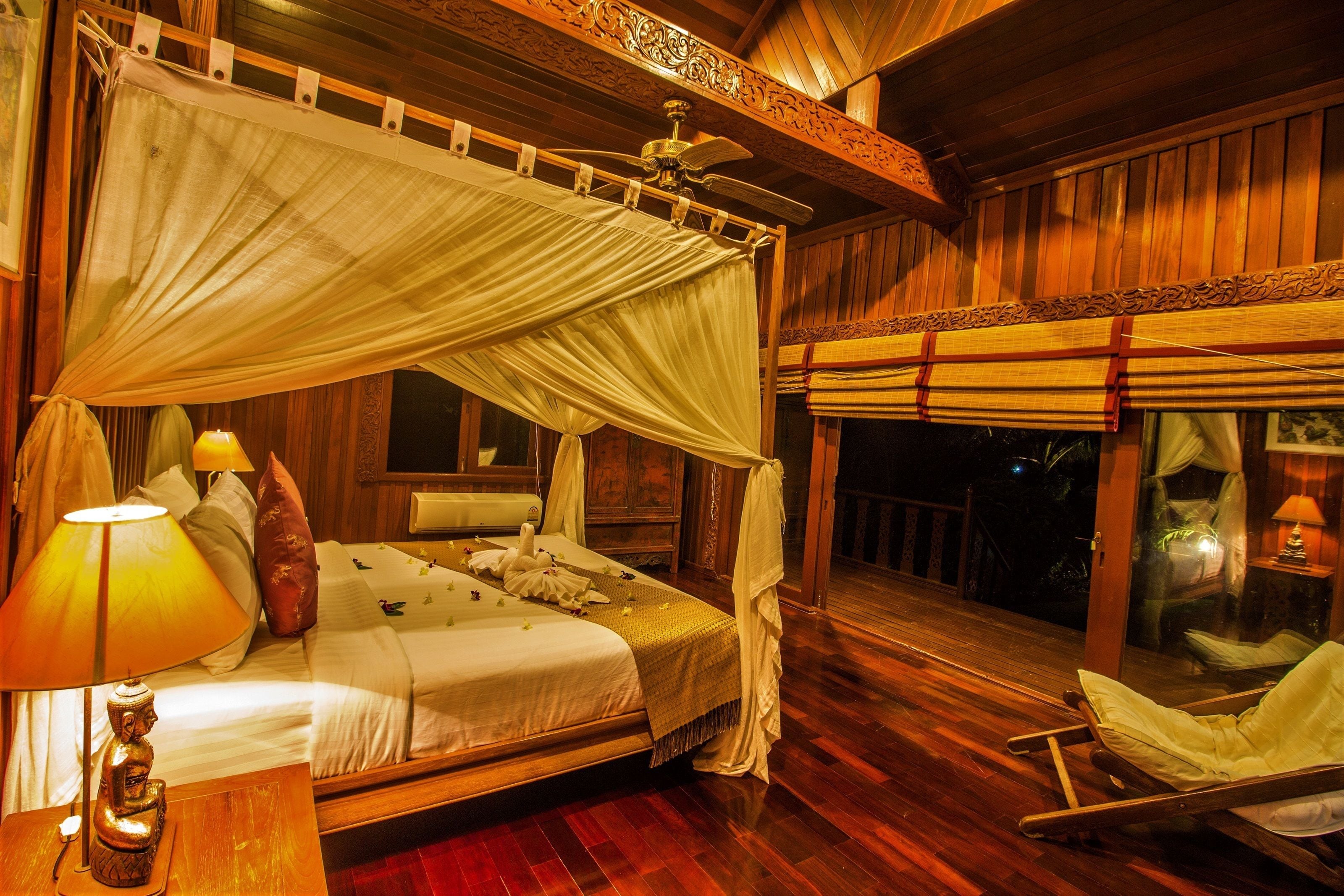 A room with a bed, a nightstand, a chair, and a balcony with a view.