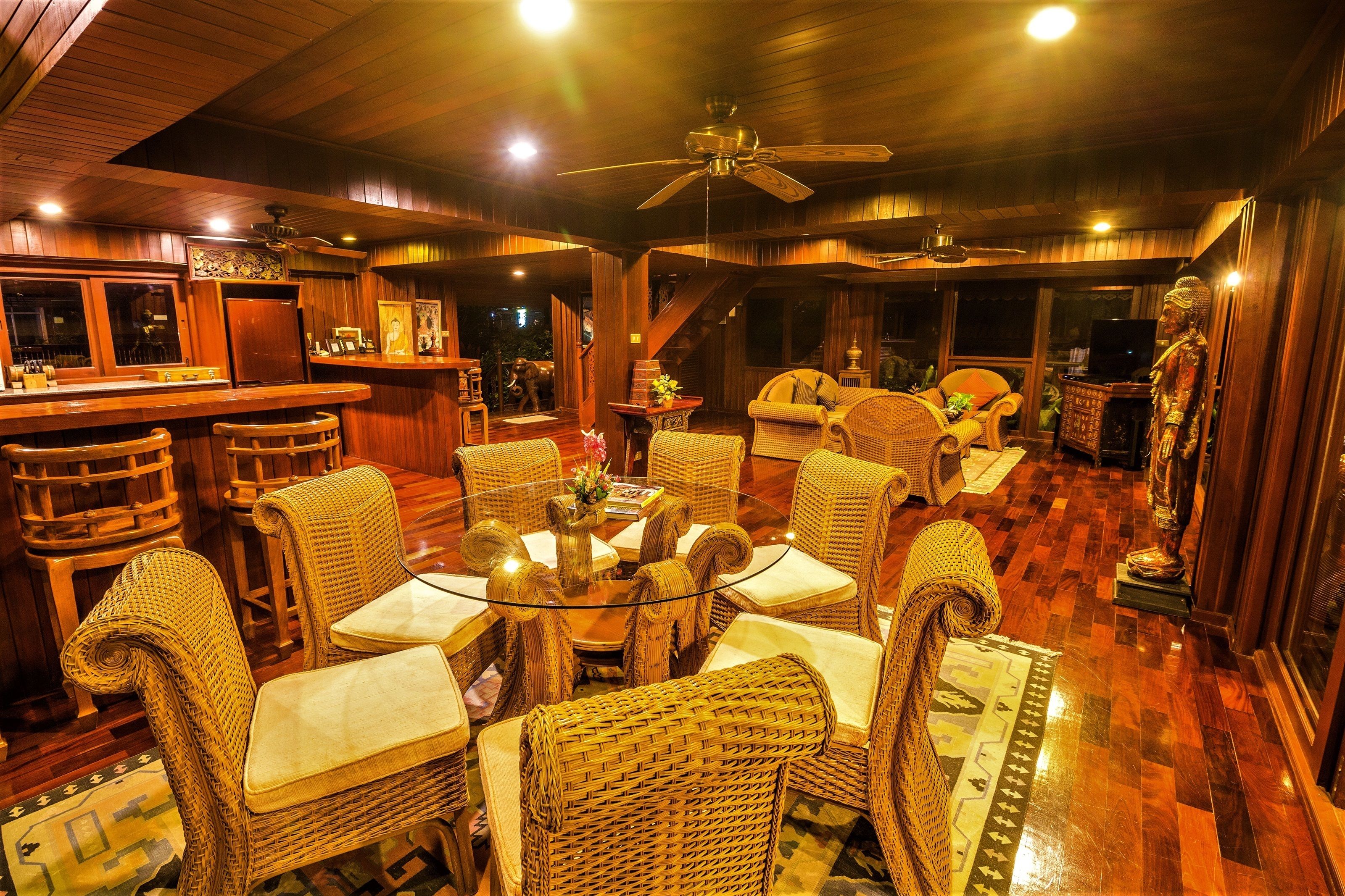 A cozy, well-lit room with wicker furniture, a bar area, and a statue.