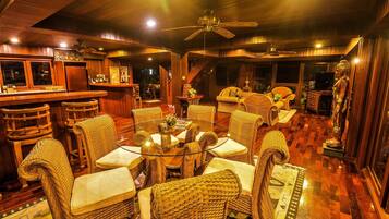 A cozy, well-lit room with wicker furniture, a bar area, and a statue.