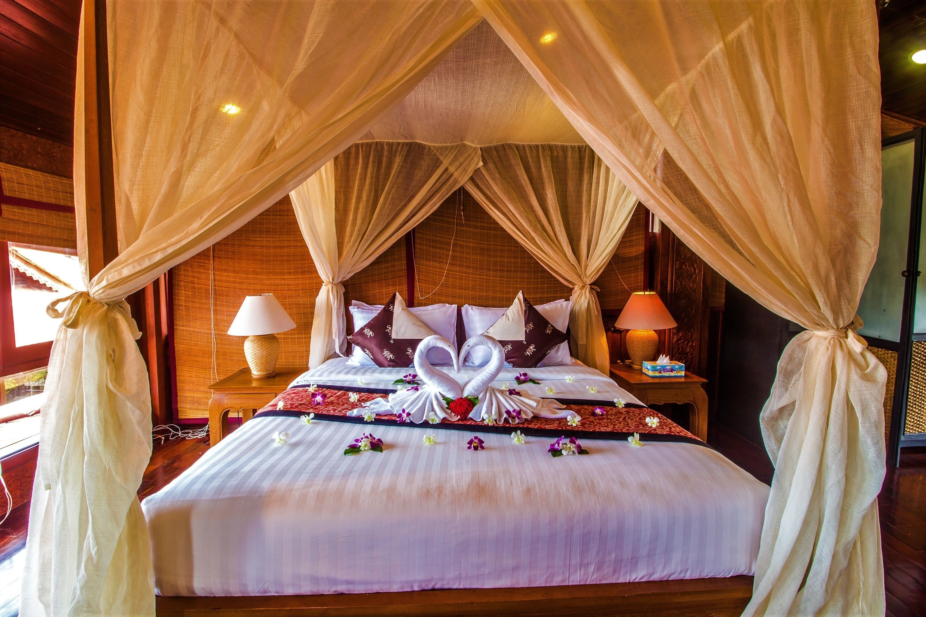 A bed with a canopy, pillows, and a floral arrangement.