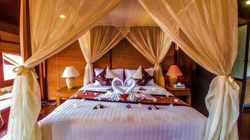 A bed with a canopy, pillows, and a floral arrangement.