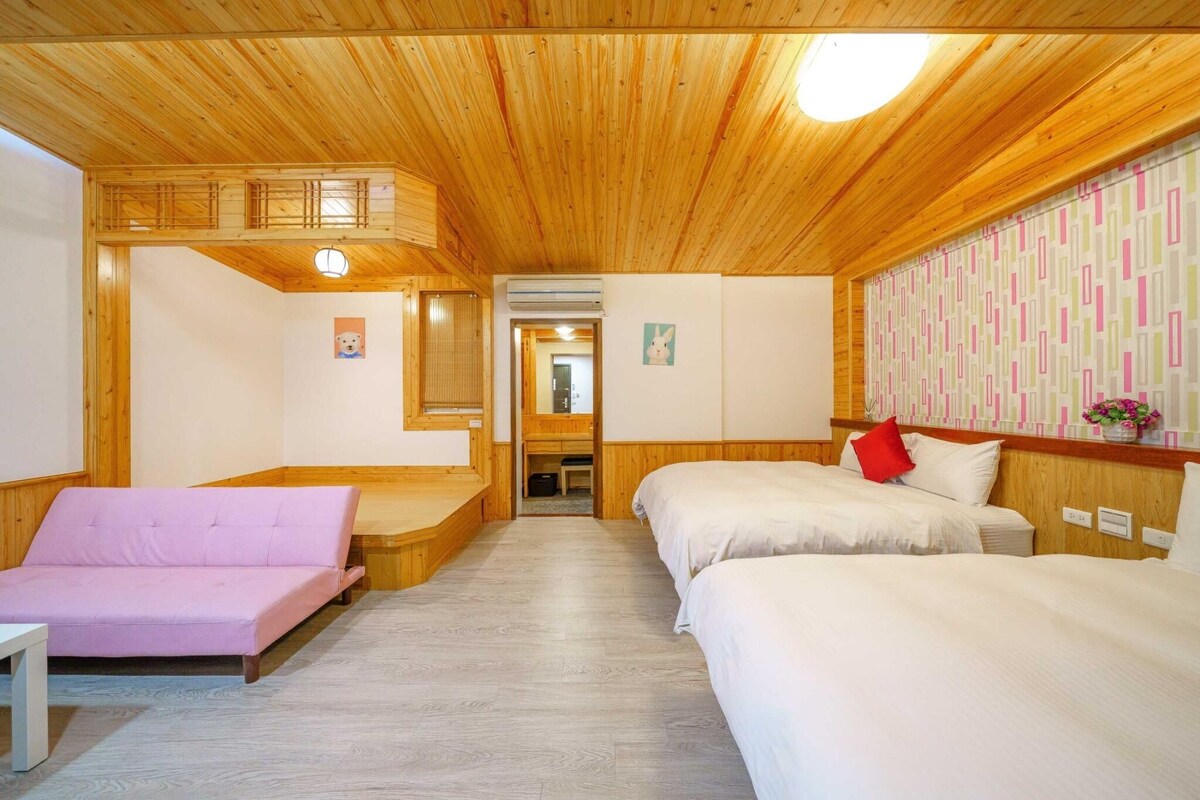 Een houten hutje met een gezellig interieur, met een bank, twee bedden en een kleine tafel.