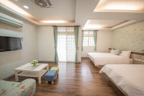 A hotel room with a wooden floor, two beds, a TV, a small table with a flower vase, and a window with curtains. - Smile Corner LuoDong (Luodong)
