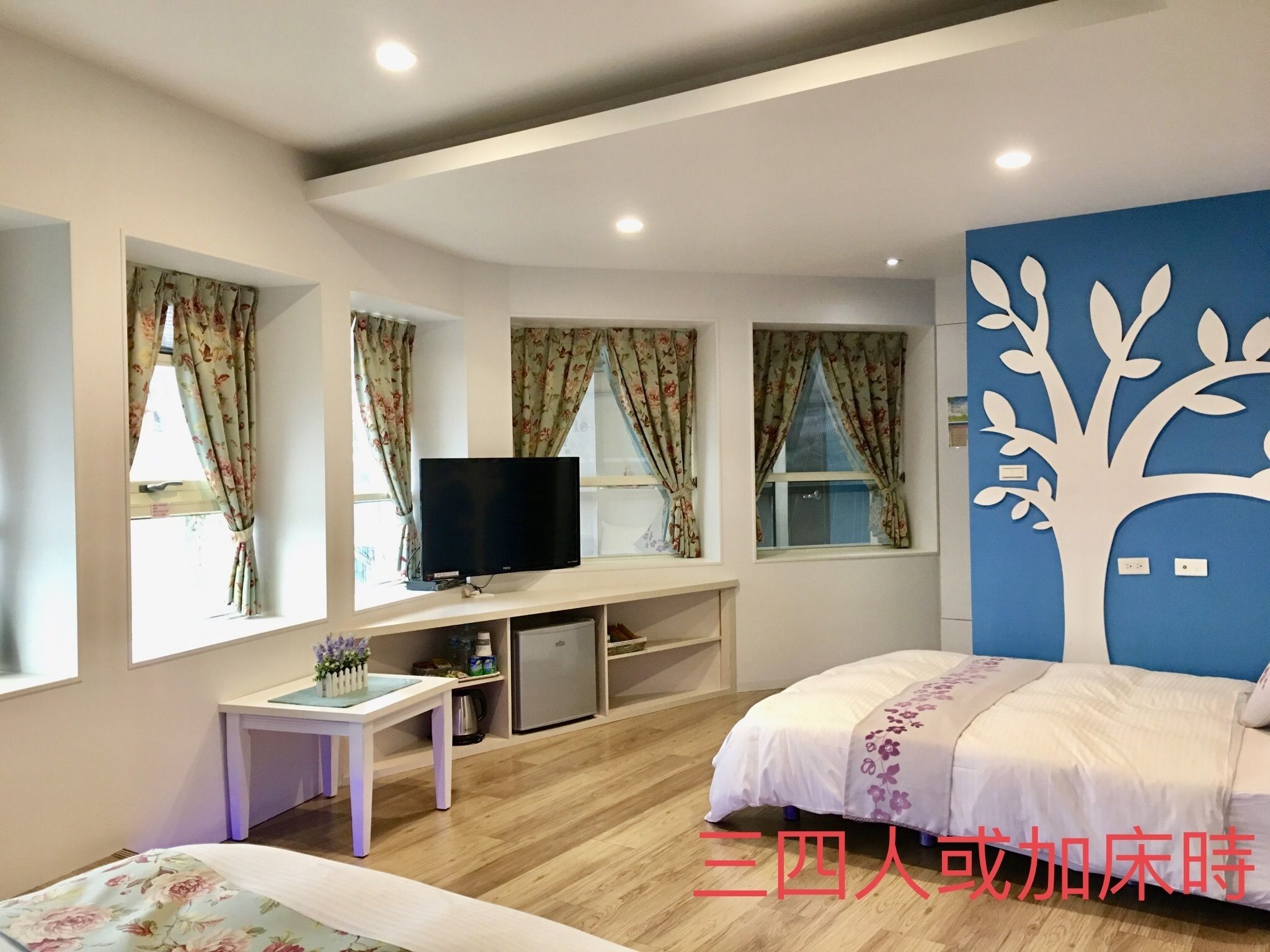 Un dormitorio con cama, televisor, escritorio y cómoda.