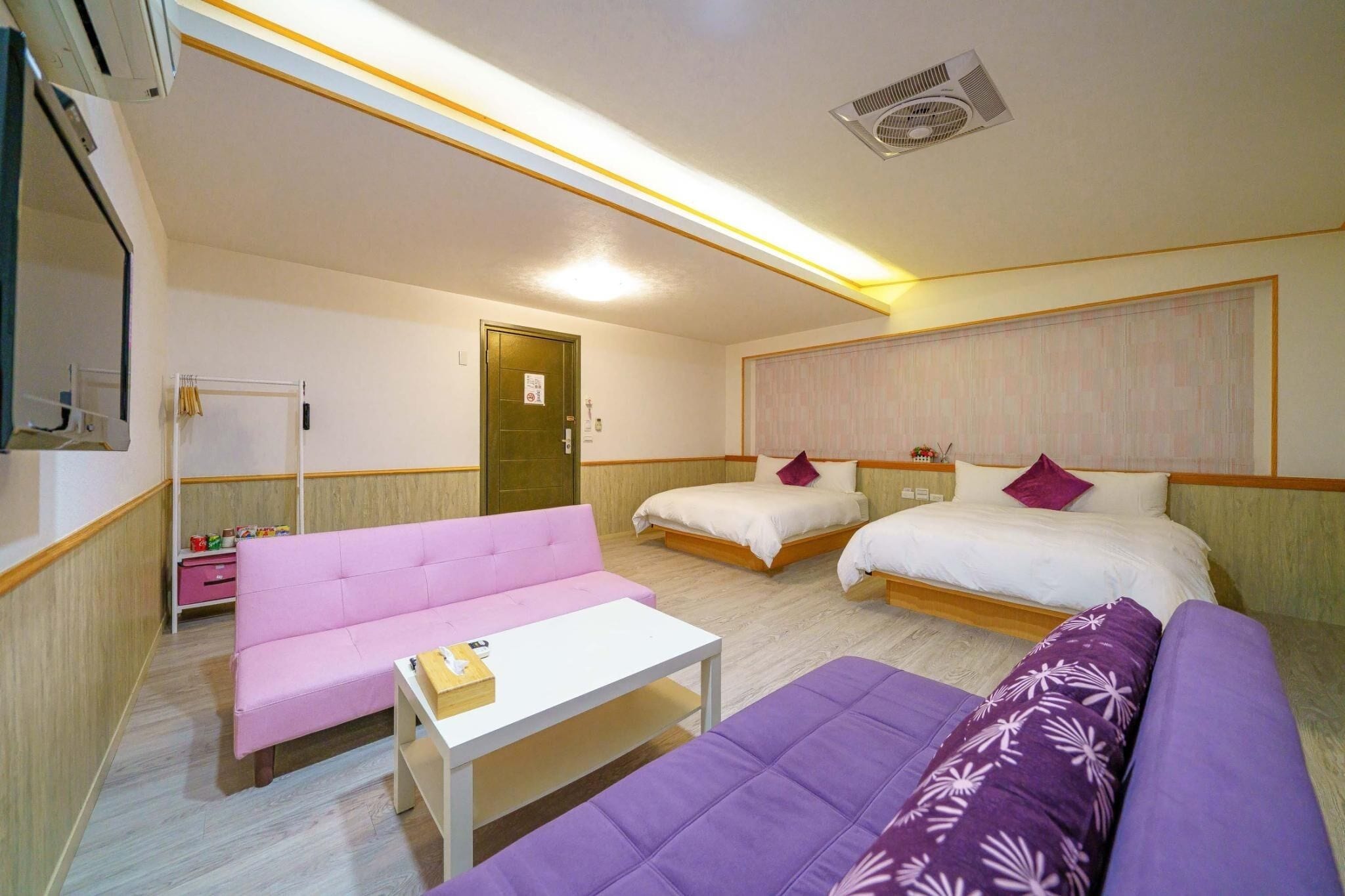 A hotel room with two beds, a sofa, a small table, and a wardrobe.