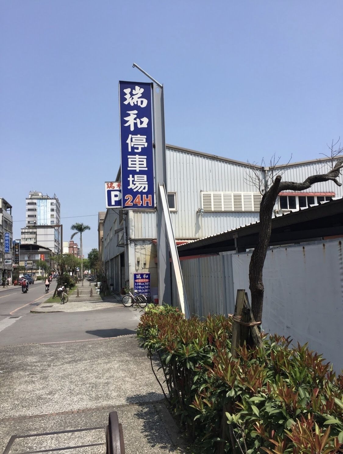 A street scene with a blue sign indicating a parking area.