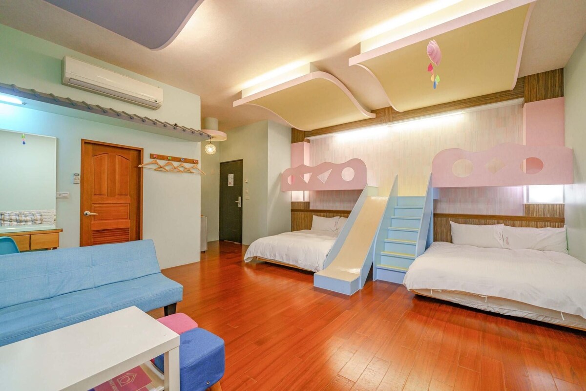 Een kamer met twee bedden, een bank, een tafeltje en een trap.
