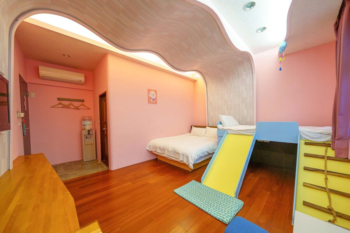Een slaapkamer met een bed, een klein bureau, een stoel, een hangstoel en een wandairconditioner.