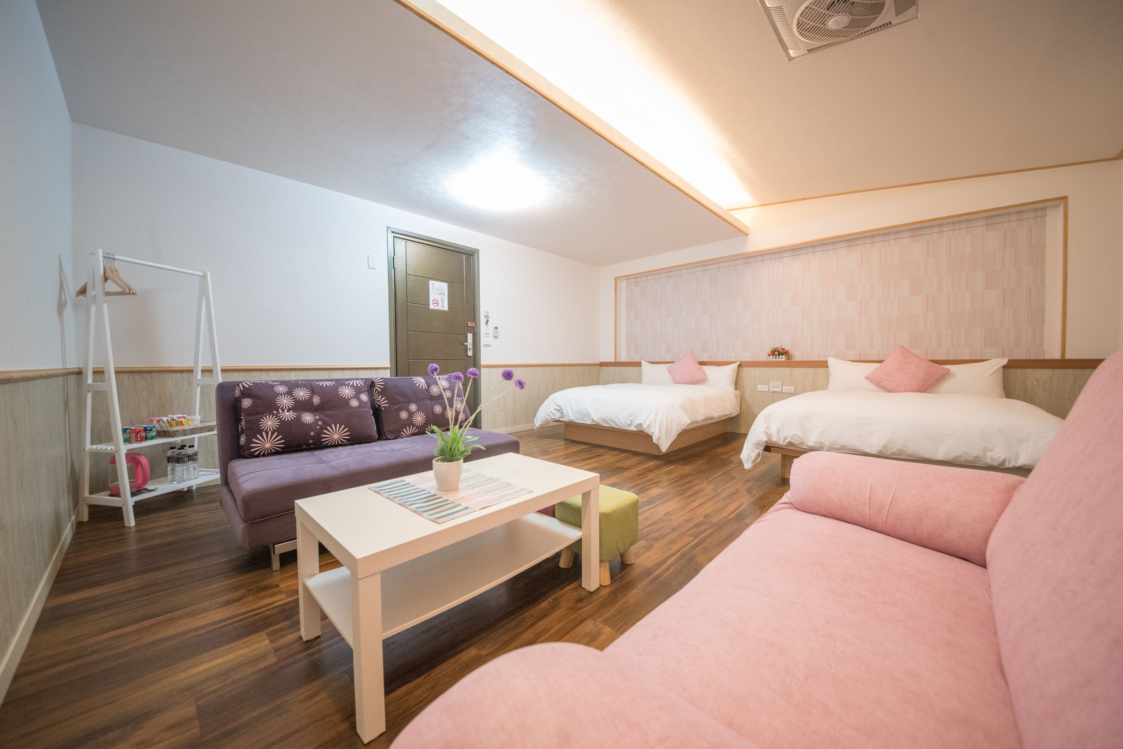 Habitación de hotel moderna con suelo de madera, sofá, cama y una mesita con una planta.