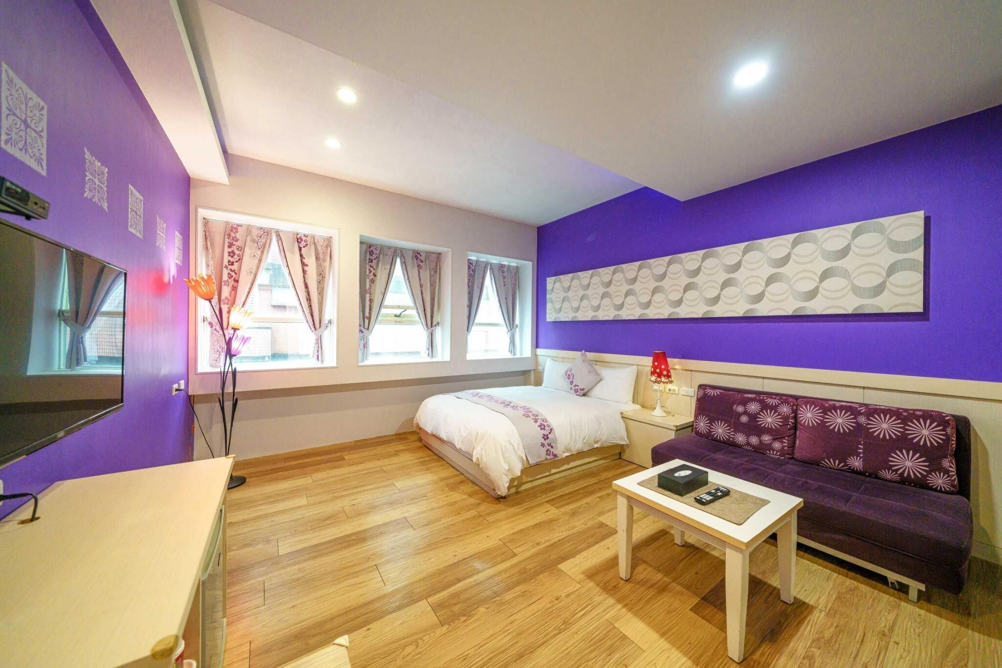 A room with a bed, a sofa, a small table, and a TV.