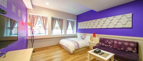 Una habitación con cama, sofá, mesita y televisor.