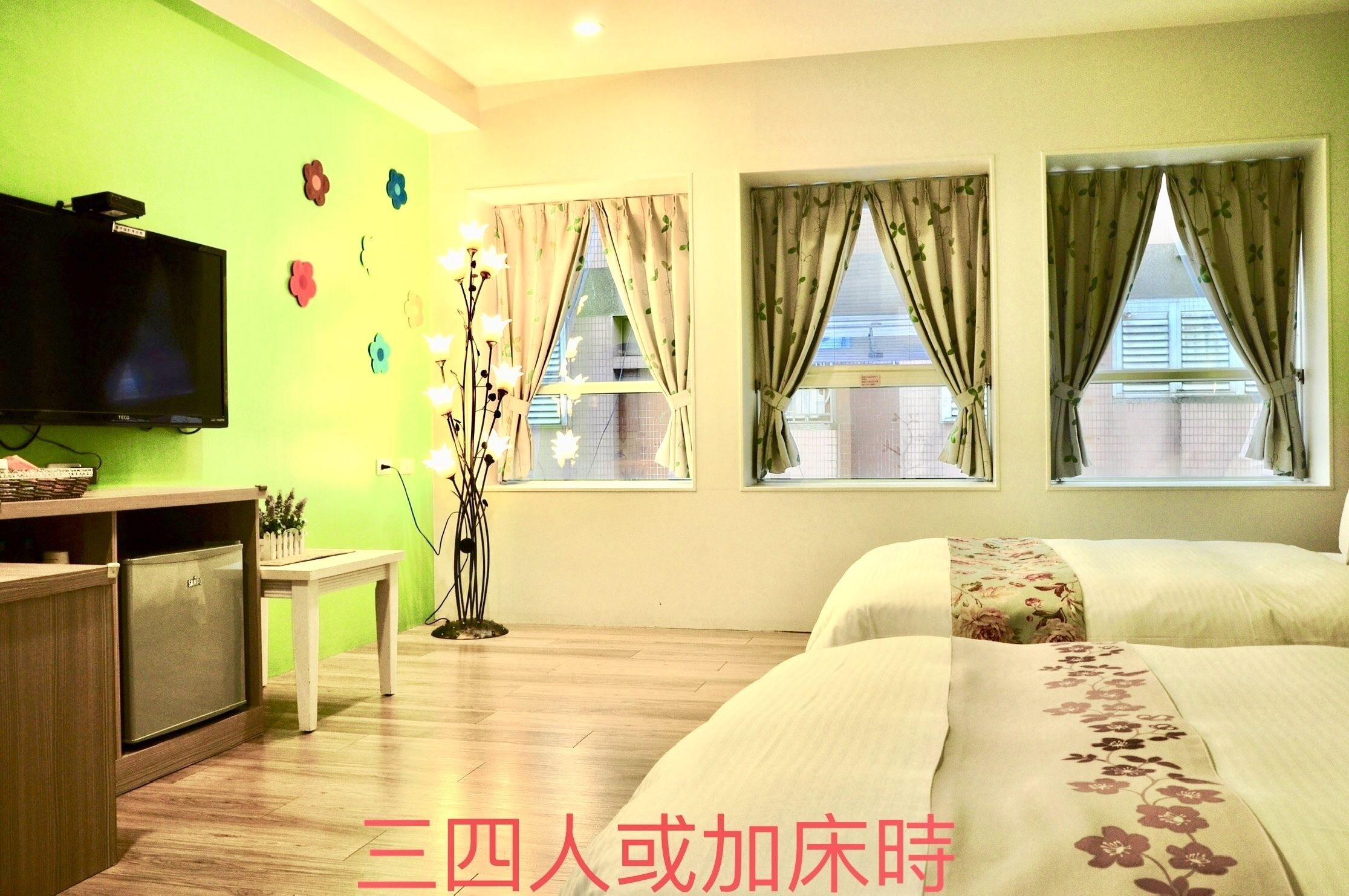 Habitación de hotel con cama, televisión, una mesita y ventana con cortinas.