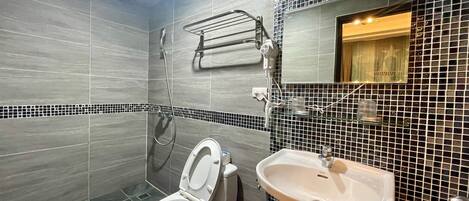 A bathroom with a toilet, a sink, a shower, and a mirror.