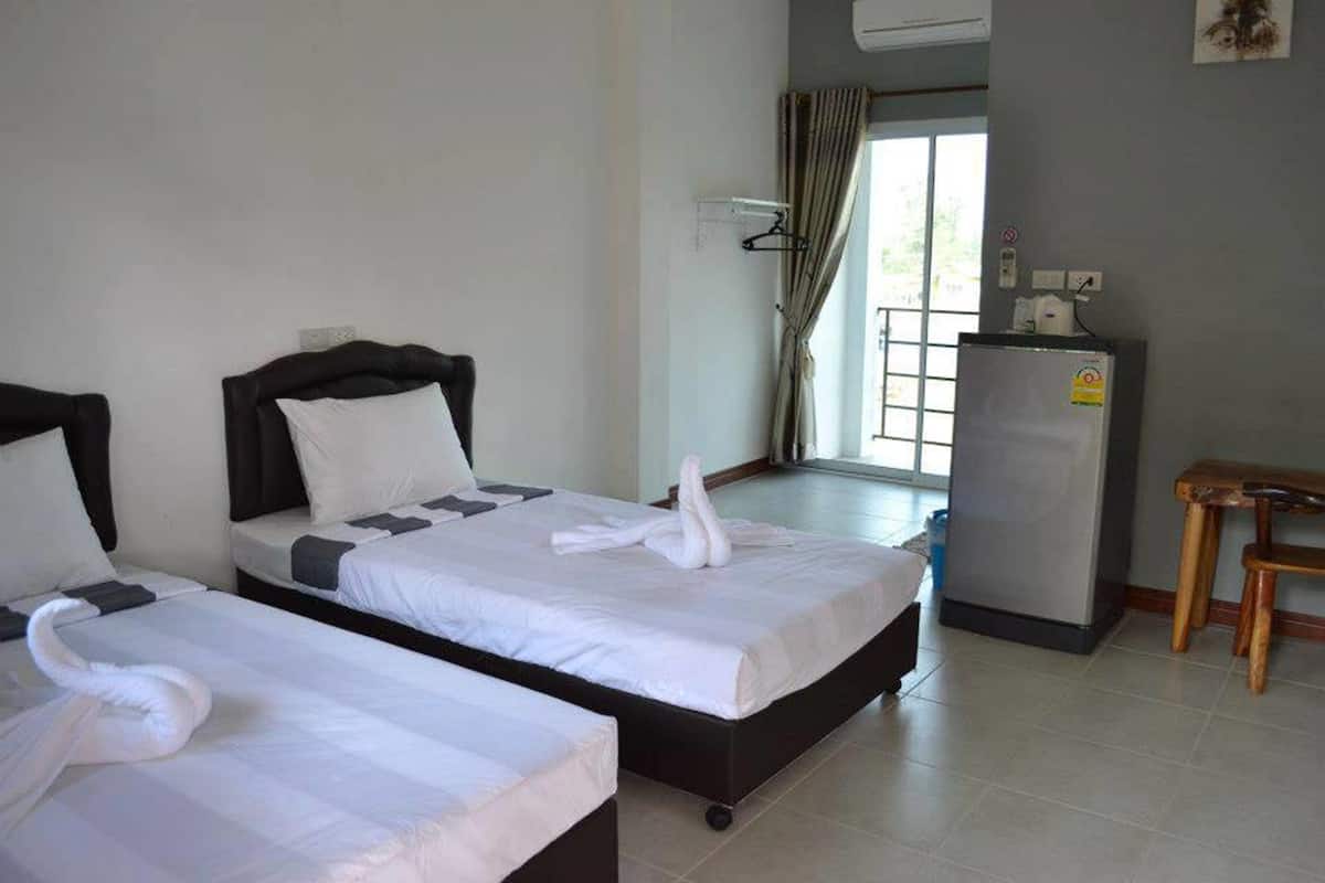 Habitación de hotel con dos camas, un escritorio y un refrigerador.