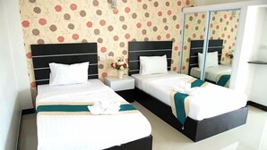 A hotel room with two beds, a large mirror, and floral wallpaper. - Phuthan Hotel (Tha Chang)