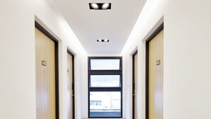 A modern hallway with wooden doors, a tiled floor, and a large window at the end. - Cypress Inn (Taitung)