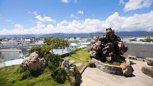 A rooftop garden with rocky terrain and a view of a cityscape. - Cypress Inn (Taitung)