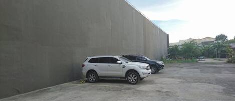 Un estacionamiento con dos SUVs, una blanca y otra negra, estacionados junto a una pared de concreto.