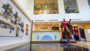 A hotel lobby with a large Iron Man statue, a reception desk, and a modern chandelier. - Heroes Hotel (Manila)