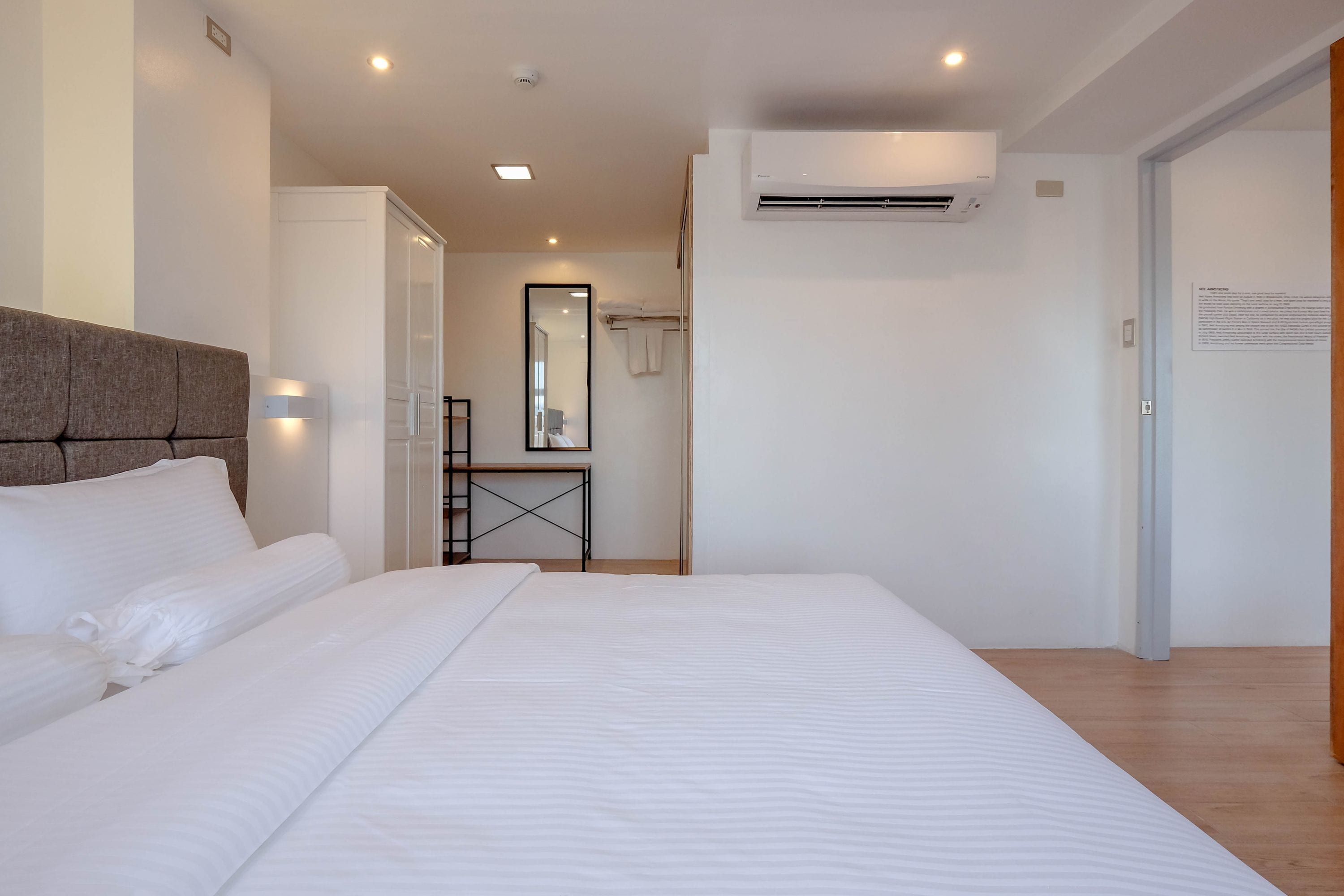 Une chambre d’hôtel moderne équipée d’un grand lit, d’une table de chevet, d’un miroir et d’un appareil de climatisation.
