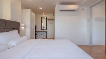 Une chambre d’hôtel moderne équipée d’un grand lit, d’une table de chevet, d’un miroir et d’un appareil de climatisation.