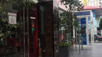 L’entrée d’un hôtel, avec une façade en verre, une enseigne d’accueil et une porte dotée d’un cadre rouge.