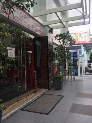 A hotel entrance with a glass facade, a welcome sign, and a door with a red frame. - Heroes Hotel (Manila)