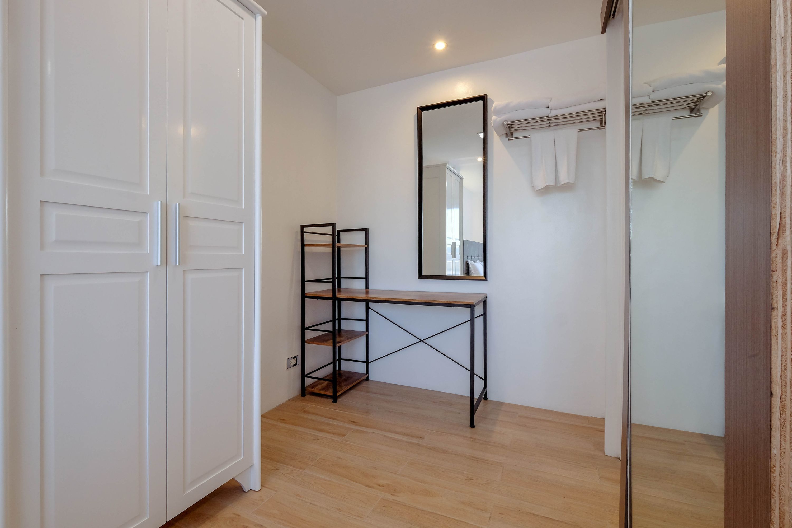 Ein modernes Badezimmer mit einem Holzkosmetikschrank, einem großen Spiegel und einem weißen Kleiderschrank.