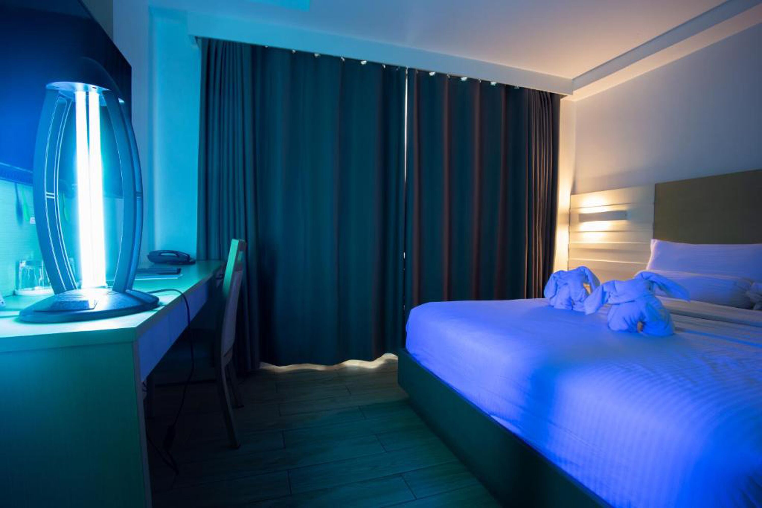 Una habitación de hotel con una cama, un escritorio con una lámpara y una cortina.