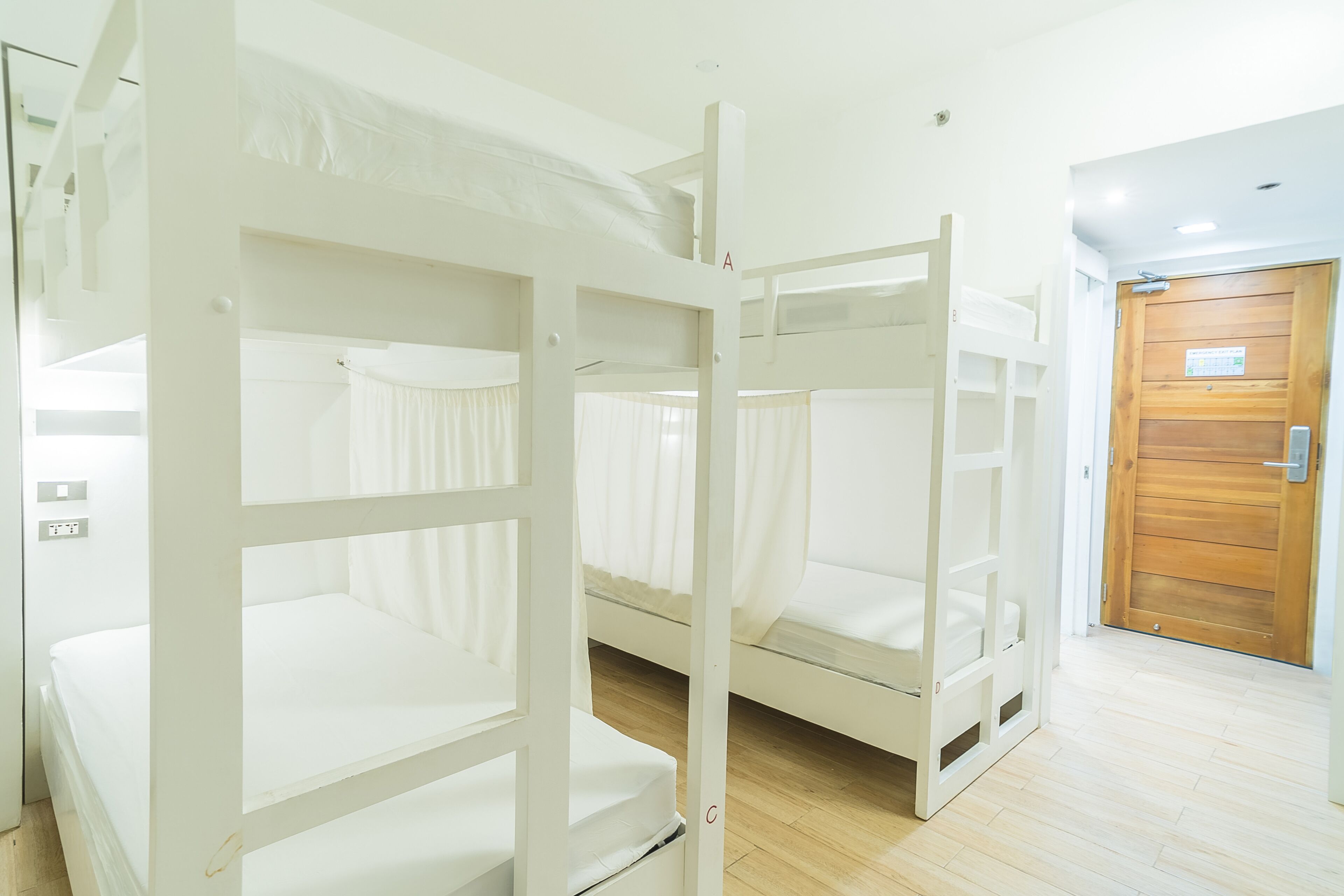 A bunk bed room with a wooden door and a light switch on the wall.