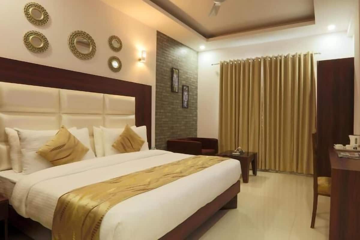 Una habitación de hotel con una cama grande, televisión, escritorio y zona de estar.