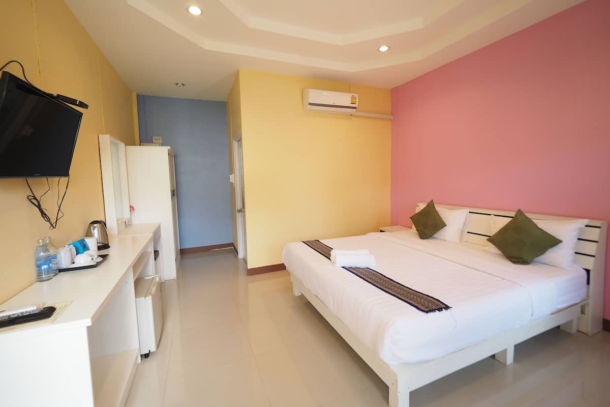 Habitación de hotel con una cama, un escritorio con ordenador, televisor y aire acondicionado.
