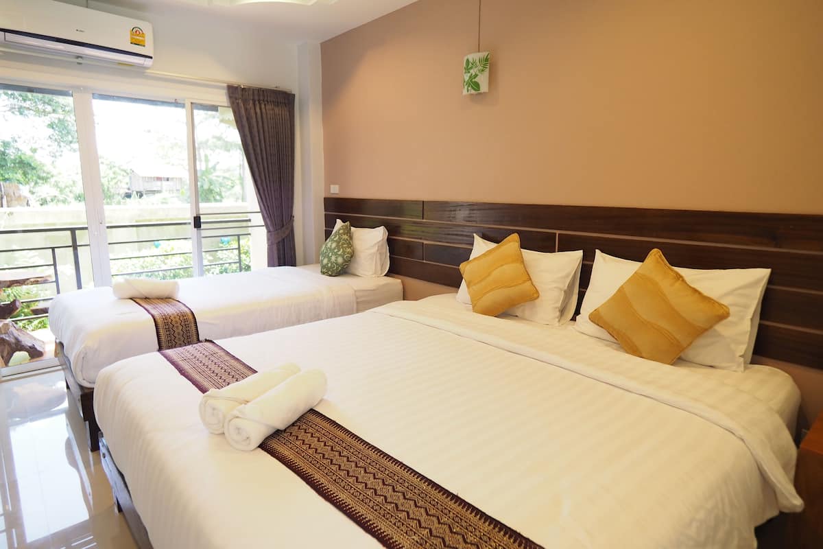 Habitación de hotel con dos camas, balcón y aire acondicionado.