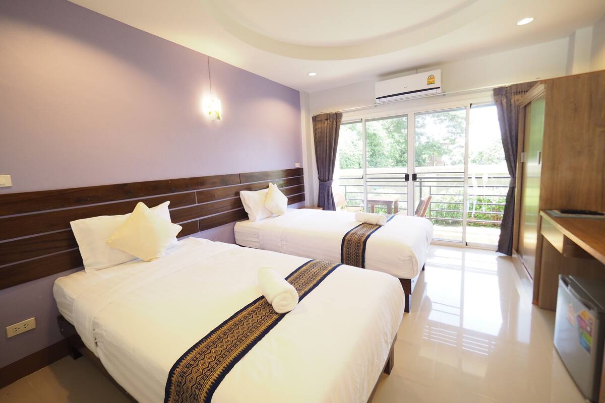 Habitación de hotel con dos camas, un balcón y un kitchenette.