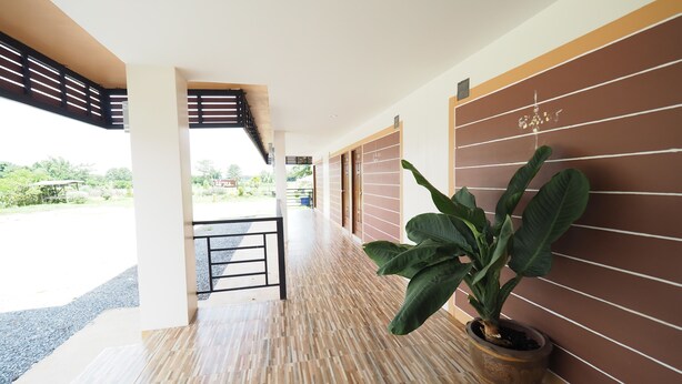 A hallway with a potted plant, wooden flooring, and a view of the outdoors. - Nan For You Resort (Phu Phiang)