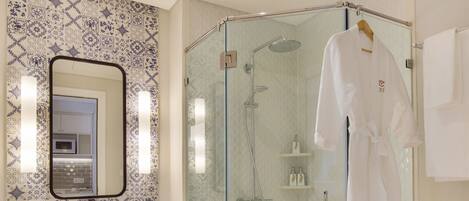 A modern bathroom with a glass-enclosed shower, a white sink, and a wooden bench.