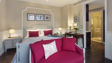 A bedroom with a bed, bedside tables, a nightstand, a dresser, a mirror, and a door leading to a bathroom.