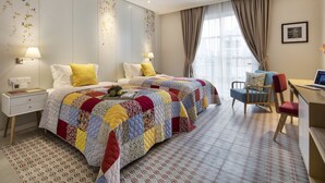 A hotel room with a large bed, a desk with a computer, a chair, and a ceiling fan. - Maison De Camille Boutique Hotel (Ho Chi Minh City)