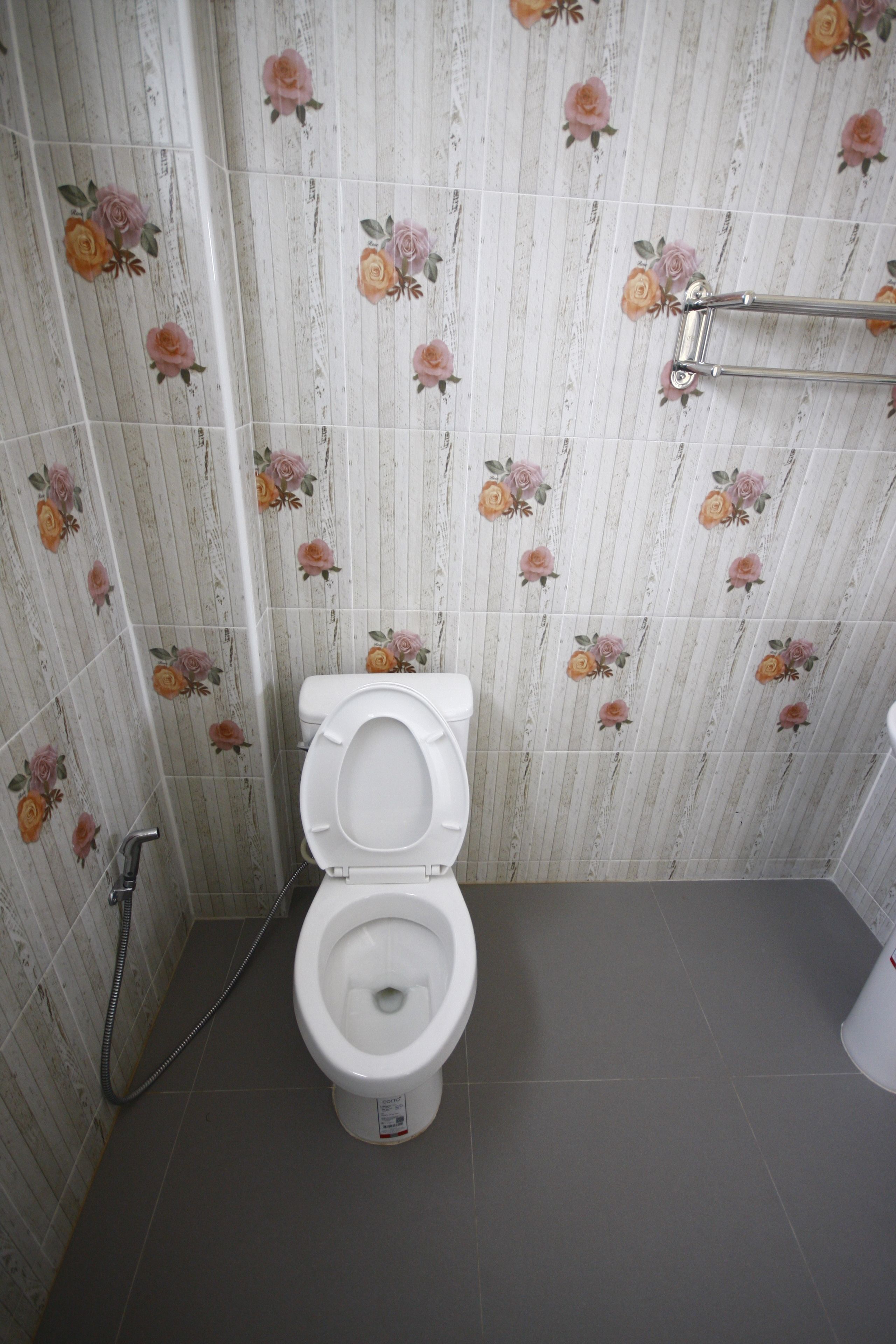 A bathroom with a toilet, a shower, and a toilet paper holder.