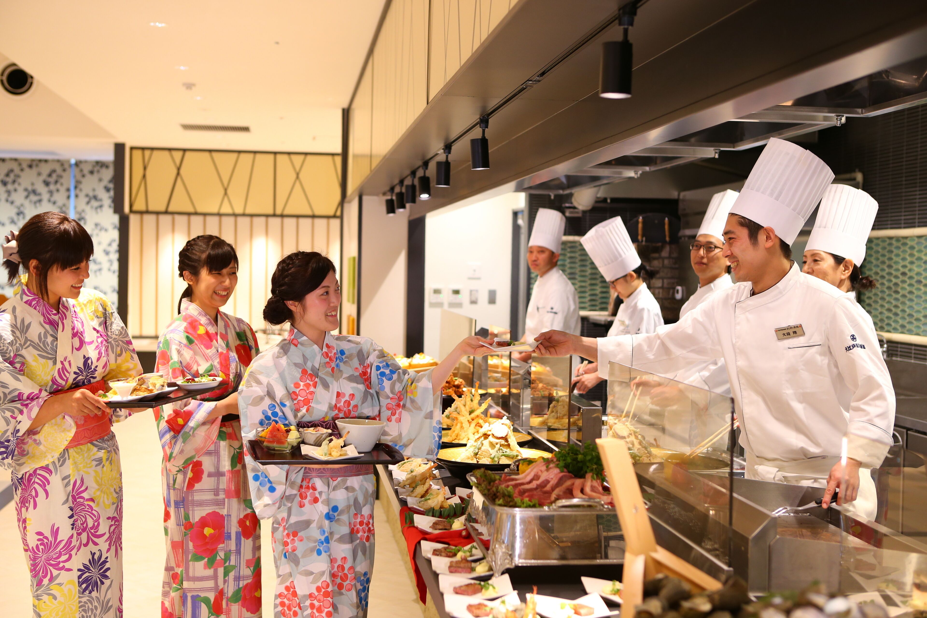 A buffet line with chefs serving food, and guests in traditional attire.