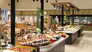 Buffet com diversos tipos de comida e um chef ao fundo.