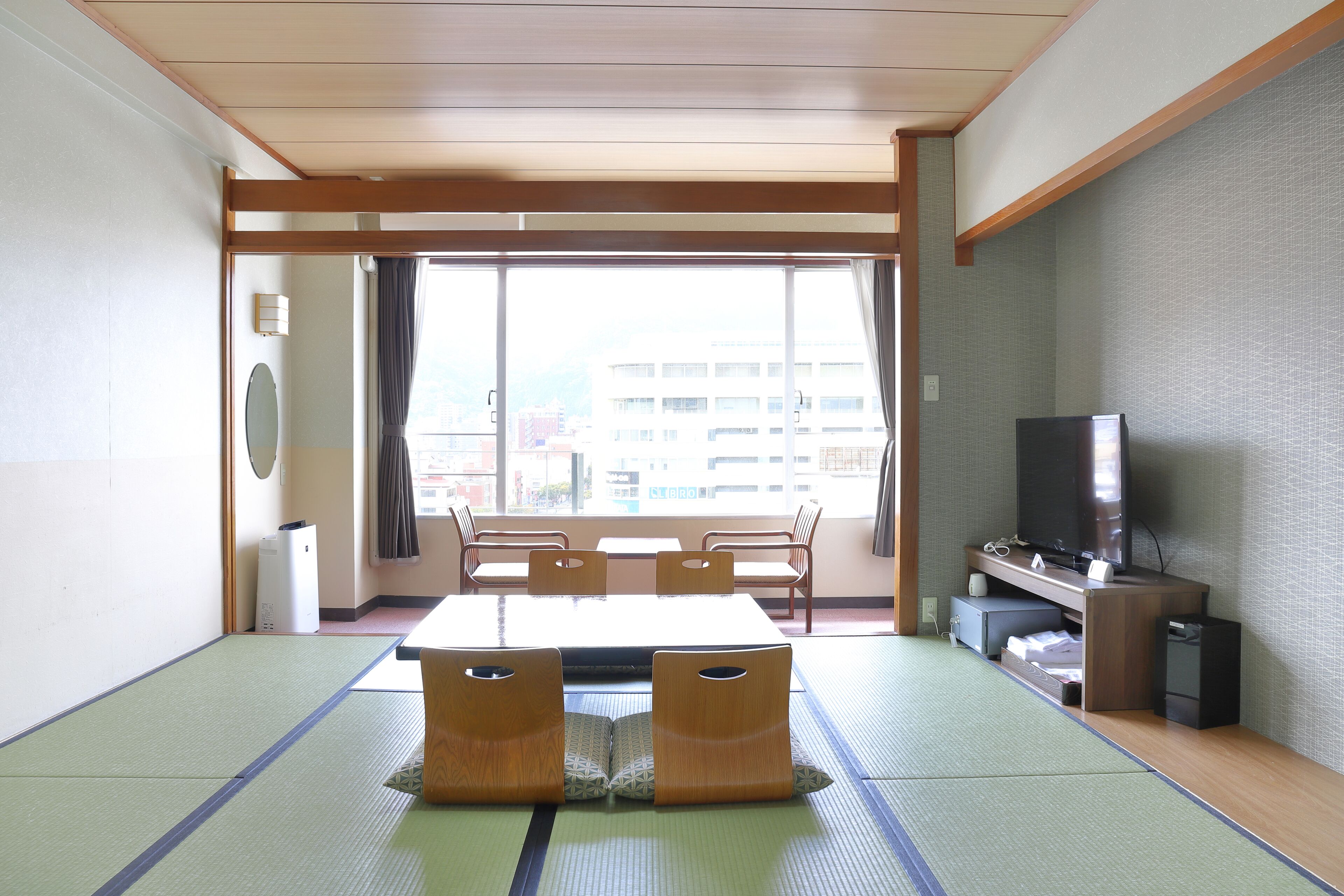 Una stanza tradizionale giapponese con pavimentazione in tatami, un tavolino e un televisore.