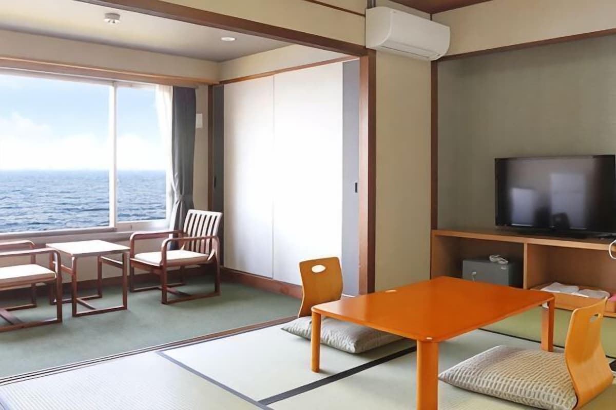 Una habitación con televisión, una mesa, sillas y vistas al mar.