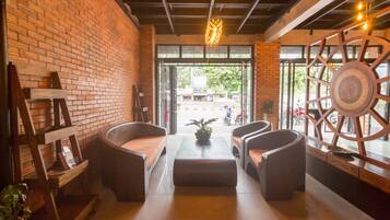 A cozy seating area with a brick wall, a large window, and a decorative metal wheel.